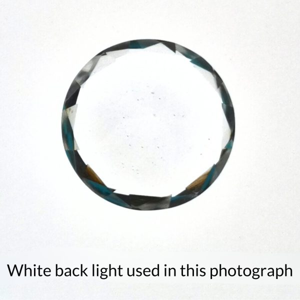 The round shaped clear quartz gem is being back-lit with a bright white light to show any inclusions within the gem more clearly.