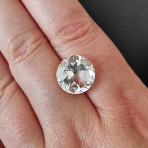 The large clear quartz gemstone resting on a hand to give an idea of the gemstones size and colour.