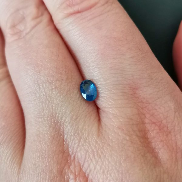 The blue sapphire gemstone resting on a hand to give an idea of the gemstones size and colour.