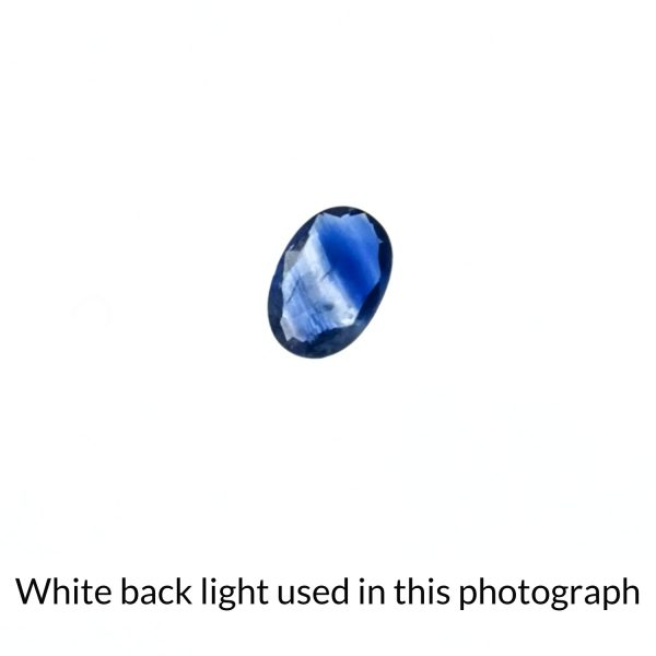 The oval shaped sapphire gem is being back-lit with a bright white light to show any inclusions within the gem more clearly.