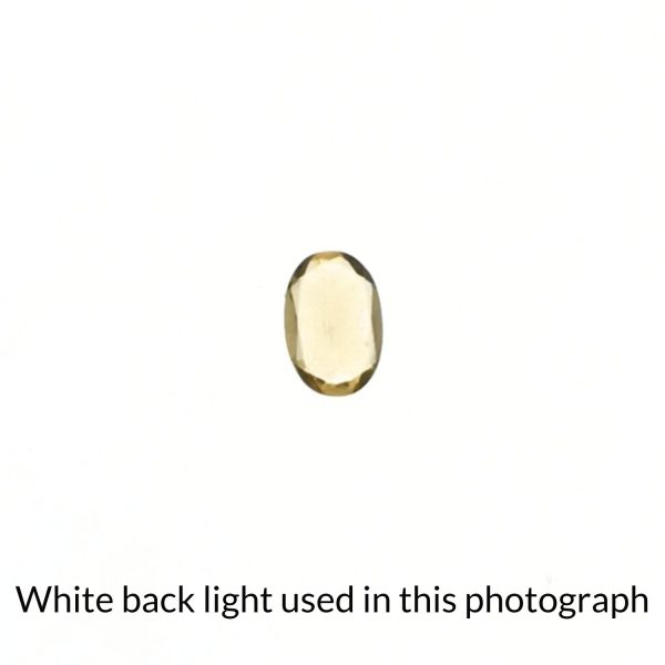 The golden heliodor oval gem is being back-lit with a bright white light to show any inclusions within the gem more clearly.