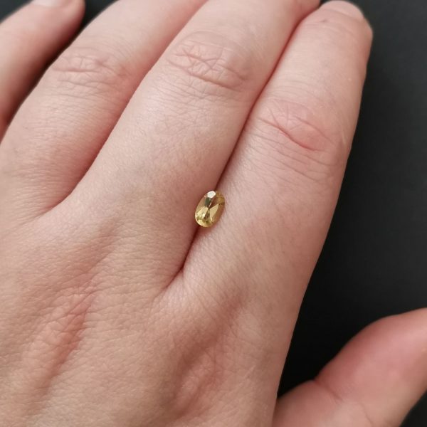 The golden yellow heliodor gemstone resting on a hand to give an idea of the gemstones size and colour.