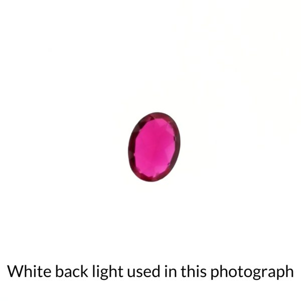 The lab grown ruby oval gem is being back-lit with a bright white light to show any inclusions within the gem more clearly.