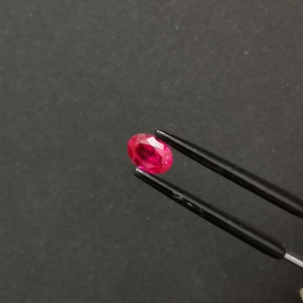 A photo of the crown area of the pinkish red lab grown ruby against a black background