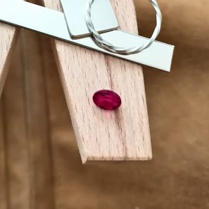 The red lab grown ruby oval displayed on a jewellers bench peg with some sterling silver sheet and wire.