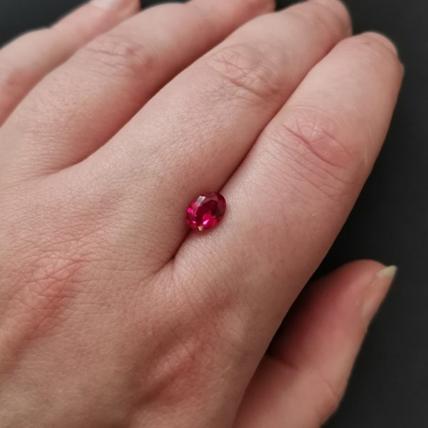 The red lab grown ruby gemstone resting on a hand to give an idea of the gemstones size and colour.