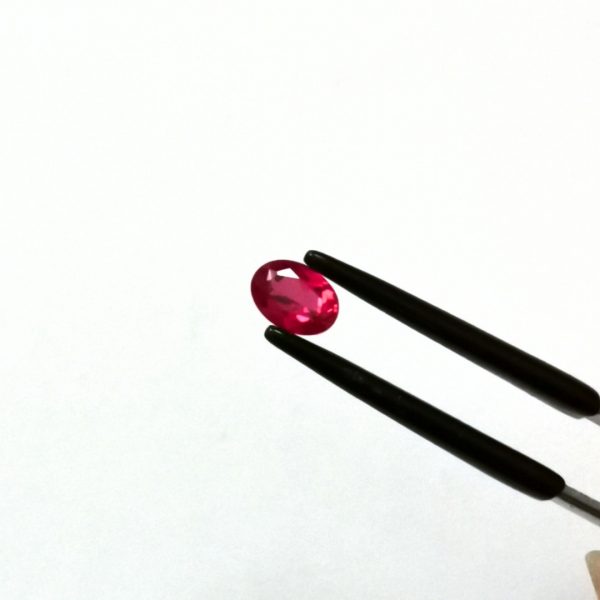 A photo of the crown area of the pinkish red lab grown ruby against a white background