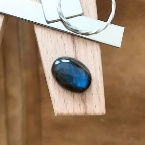 The labradorite cabochon oval displayed on a jewellers bench peg with some sterling silver sheet and wire.