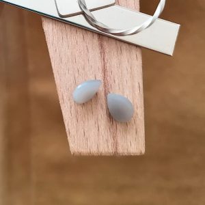 The pair of moonstone teardrops displayed on a jewellers bench peg with some sterling silver sheet and wire.