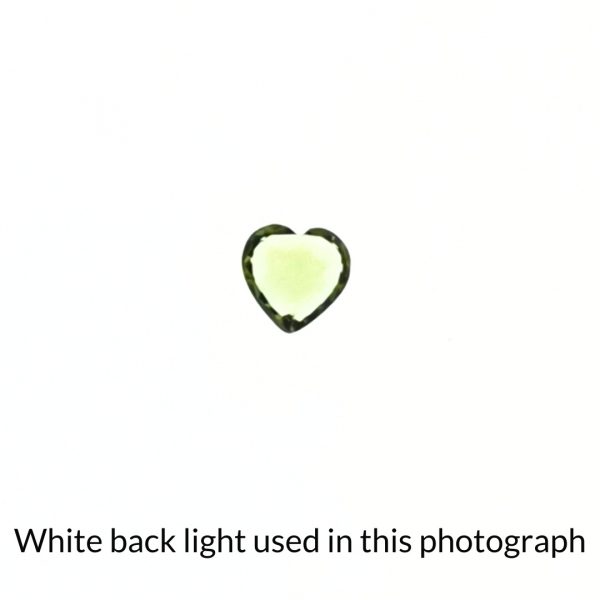The heart shaped peridot gem is being back-lit with a bright white light to show any inclusions within the gem more clearly.