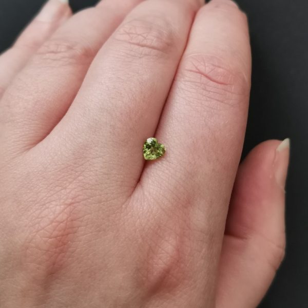 The green peridot gemstone resting on a hand to give an idea of the gemstones size and colour.
