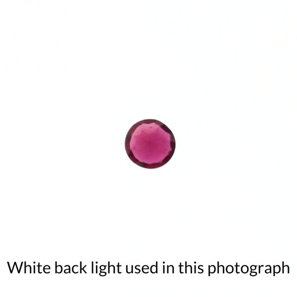 The pinkish red ruby gem is being back-lit with a bright white light to show any inclusions within the gem more clearly.