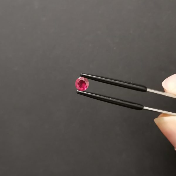 A photo of the crown area of the pinkish red ruby against a black background