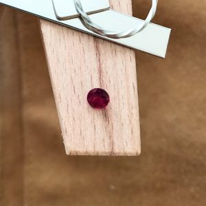 The round ruby displayed on a jewellers bench peg with some sterling silver sheet and wire.