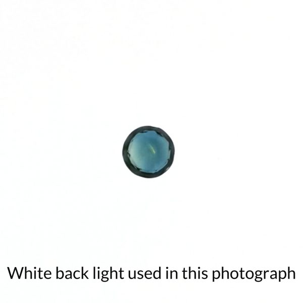 The round sapphire gem is being back-lit with a bright white light to show any inclusions within the gem more clearly.