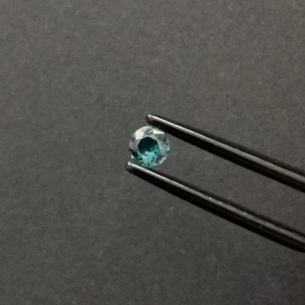 A photo of the crown area of the green-blue sapphire against a black background