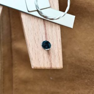 The round sapphire displayed on a jewellers bench peg with some sterling silver sheet and wire.