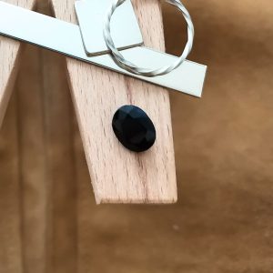 The black sapphire oval displayed on a jewellers bench peg with some sterling silver sheet and wire.
