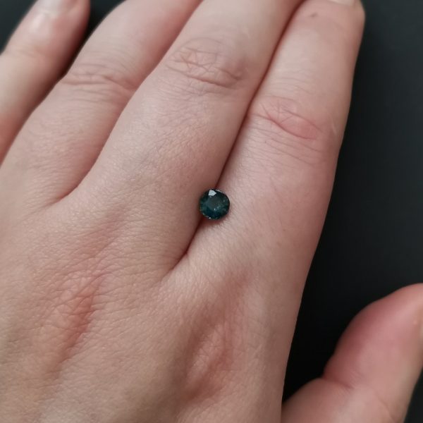 The green sapphire gemstone resting on a hand to give an idea of the gemstones size and colour.