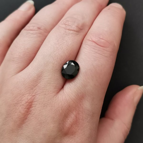 The black sapphire gemstone resting on a hand to give an idea of the gemstones size and colour.