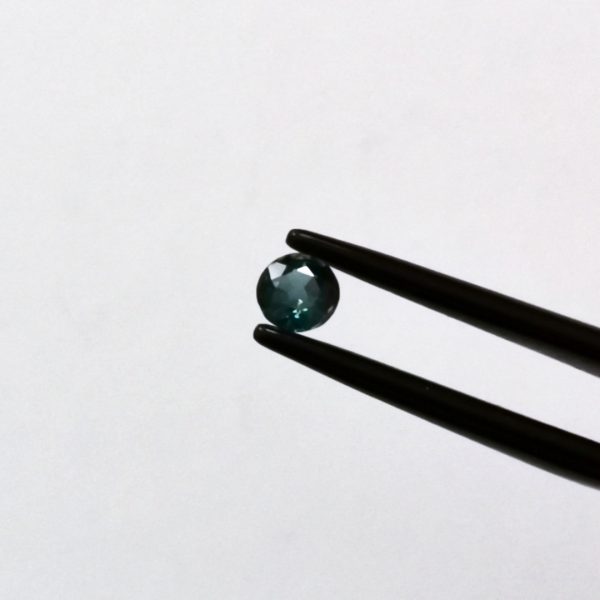 A photo of the crown area of the dark green-blue sapphire against a white background