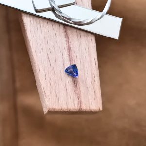 The purple-blue tanzanite triangle displayed on a jewellers bench peg with some sterling silver sheet and wire.