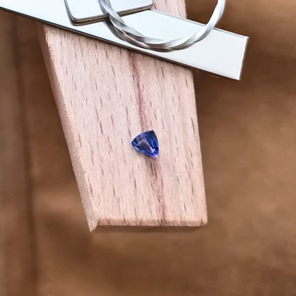 The purple-blue tanzanite triangle displayed on a jewellers bench peg with some sterling silver sheet and wire.