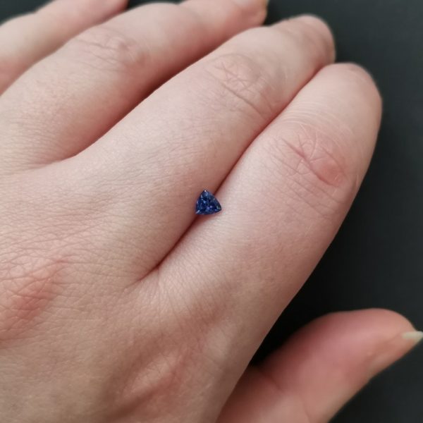 The violet tanzanite gemstone resting on a hand to give an idea of the gemstones size and colour.