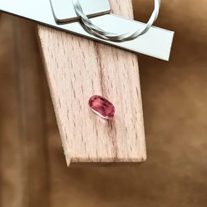 The pink tourmaline oval displayed on a jewellers bench peg with some sterling silver sheet and wire.