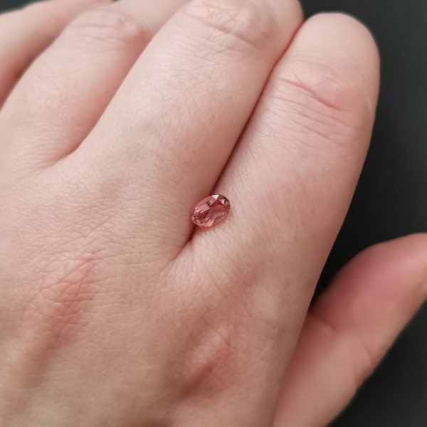The pink tourmaline gemstone resting on a hand to give an idea of the gemstones size and colour.