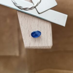 The blue sapphire oval displayed on a jewellers bench peg with some sterling silver sheet and wire.
