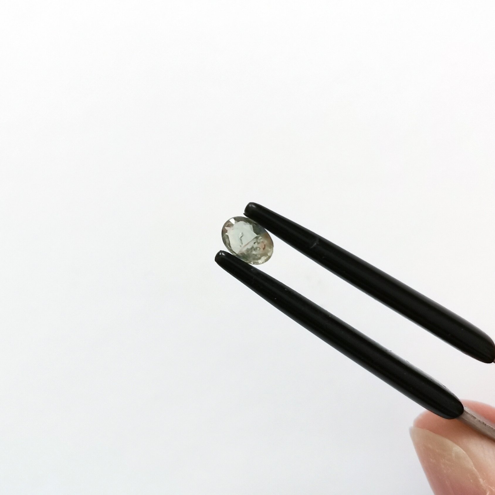 A photo of the crown area of the pale green sapphire against a white background