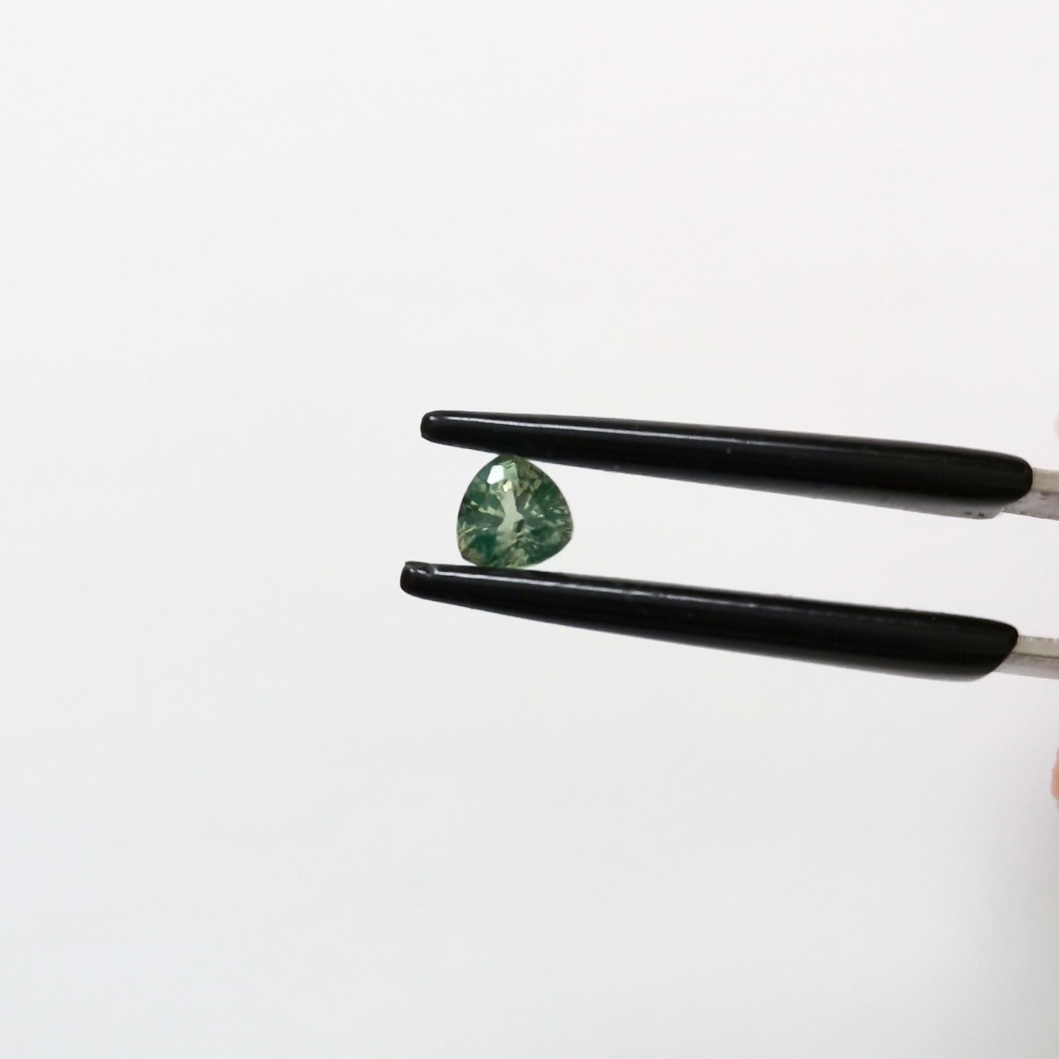 A photo of the crown area of the green sapphire against a white background