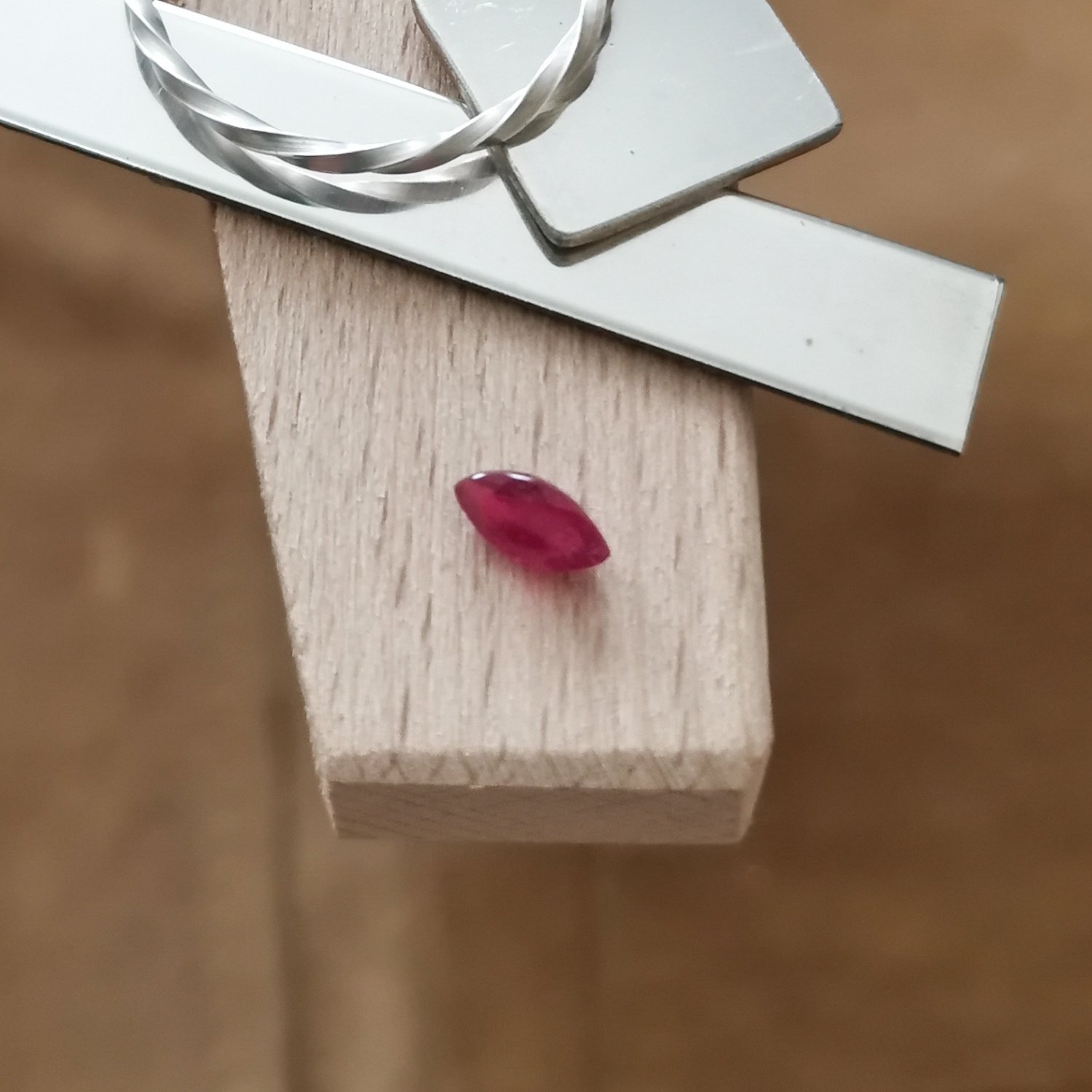 The red ruby marquise displayed on a jewellers bench peg with some sterling silver sheet and wire.