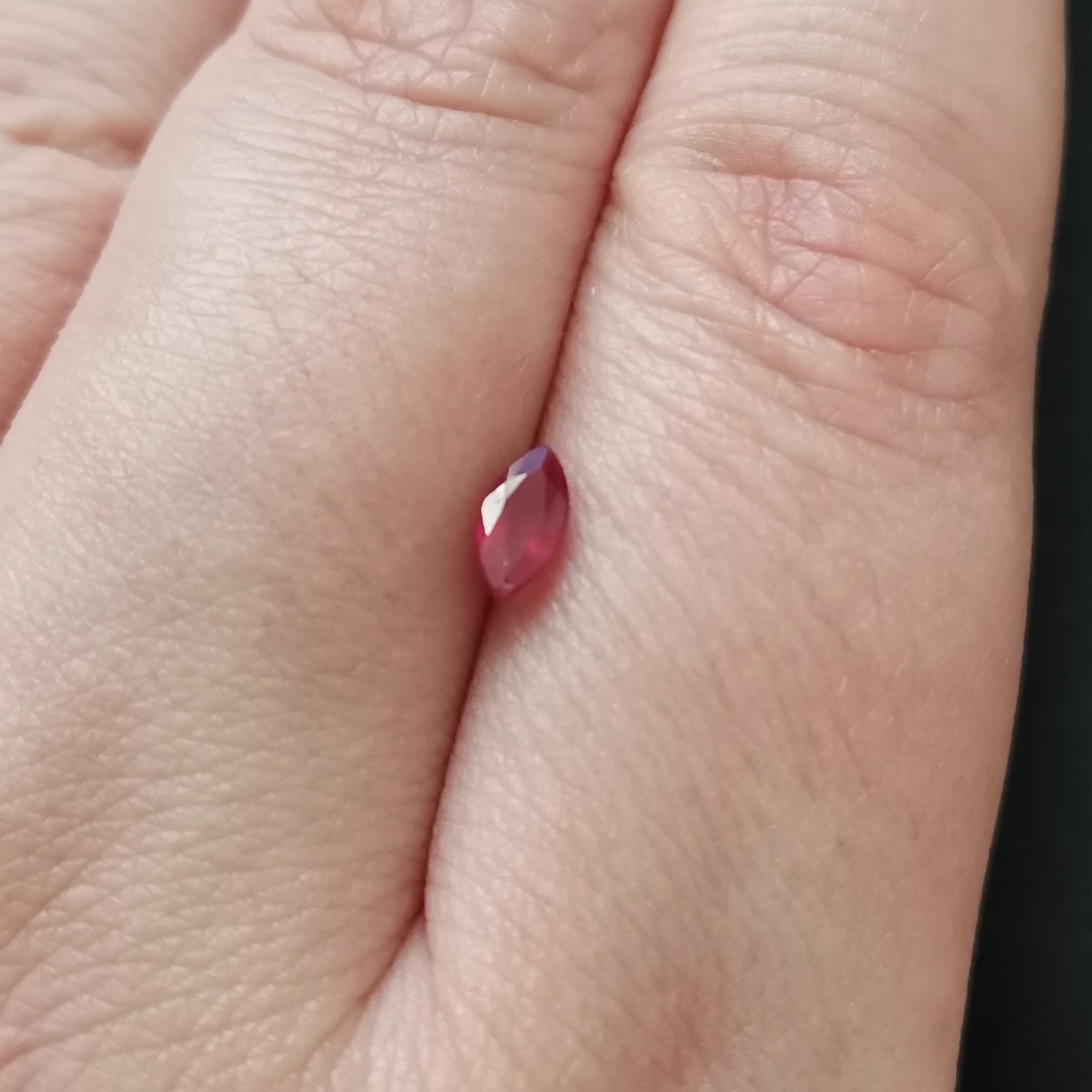 The red ruby gemstone resting on a hand to give an idea of the gemstones size and colour.