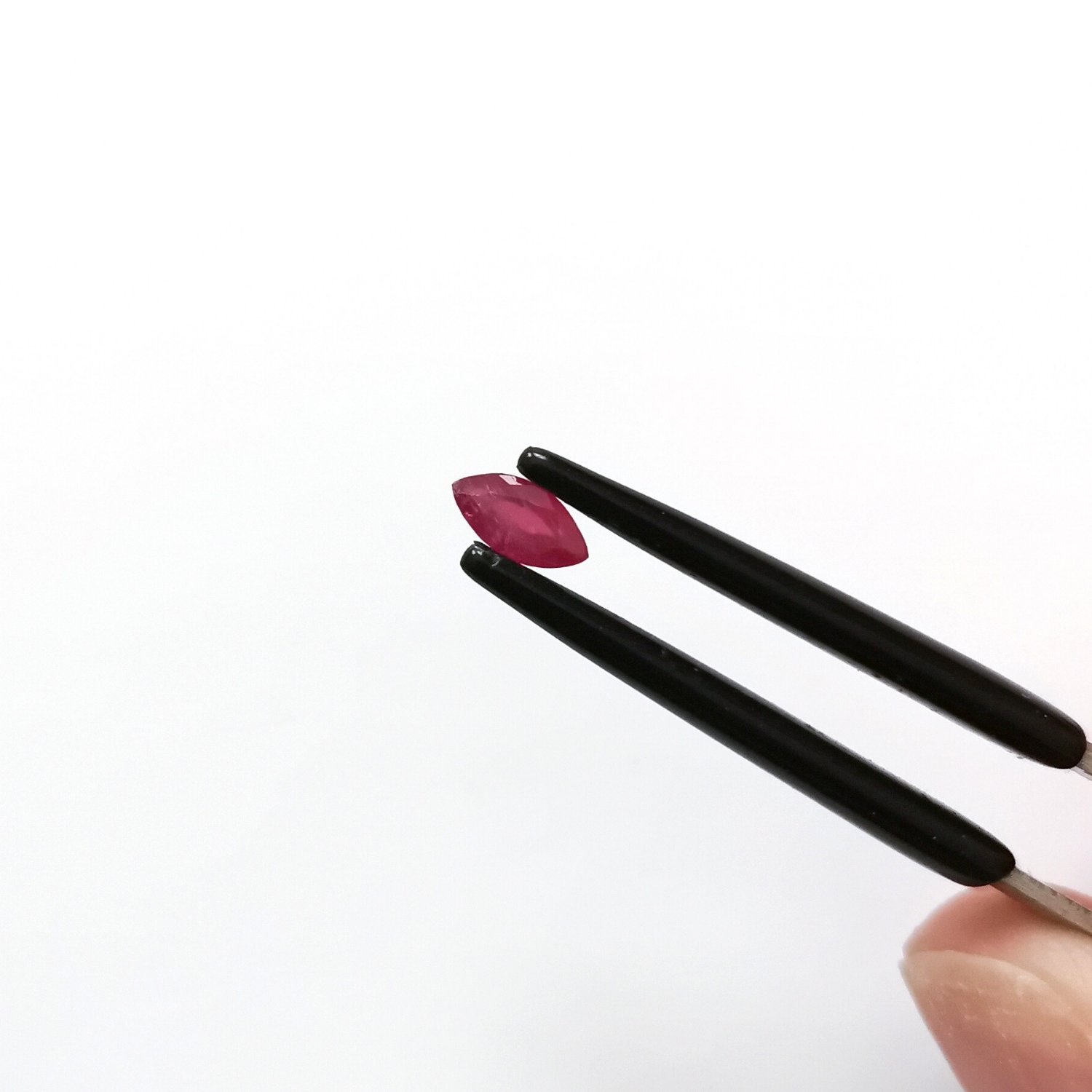 A photo of the crown area of the pinkish red ruby against a white background