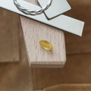 The yellow sapphire marquise displayed on a jewellers bench peg with some sterling silver sheet and wire.
