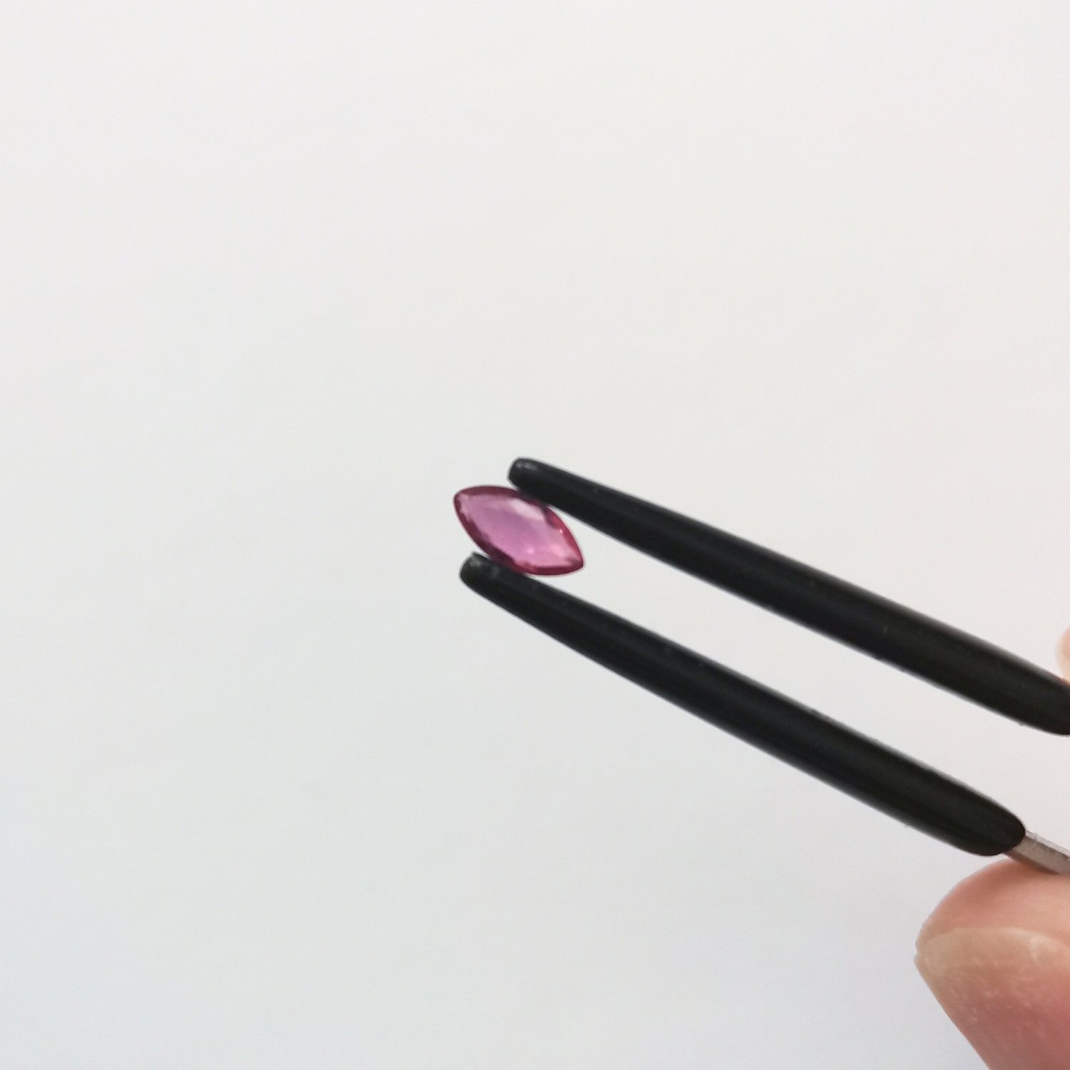A photo of the crown area of the pinkish red ruby against a white background