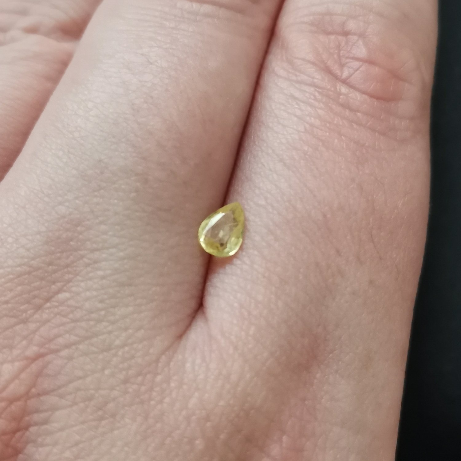 The yellow sapphire gemstone resting on a hand to give an idea of the gemstones size and colour.