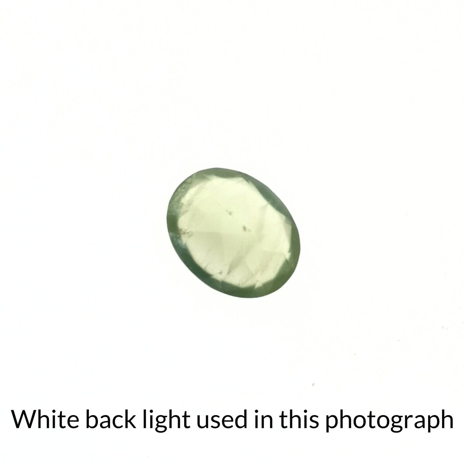 The faceted oval prehnite back-lit to highlight inclusions.