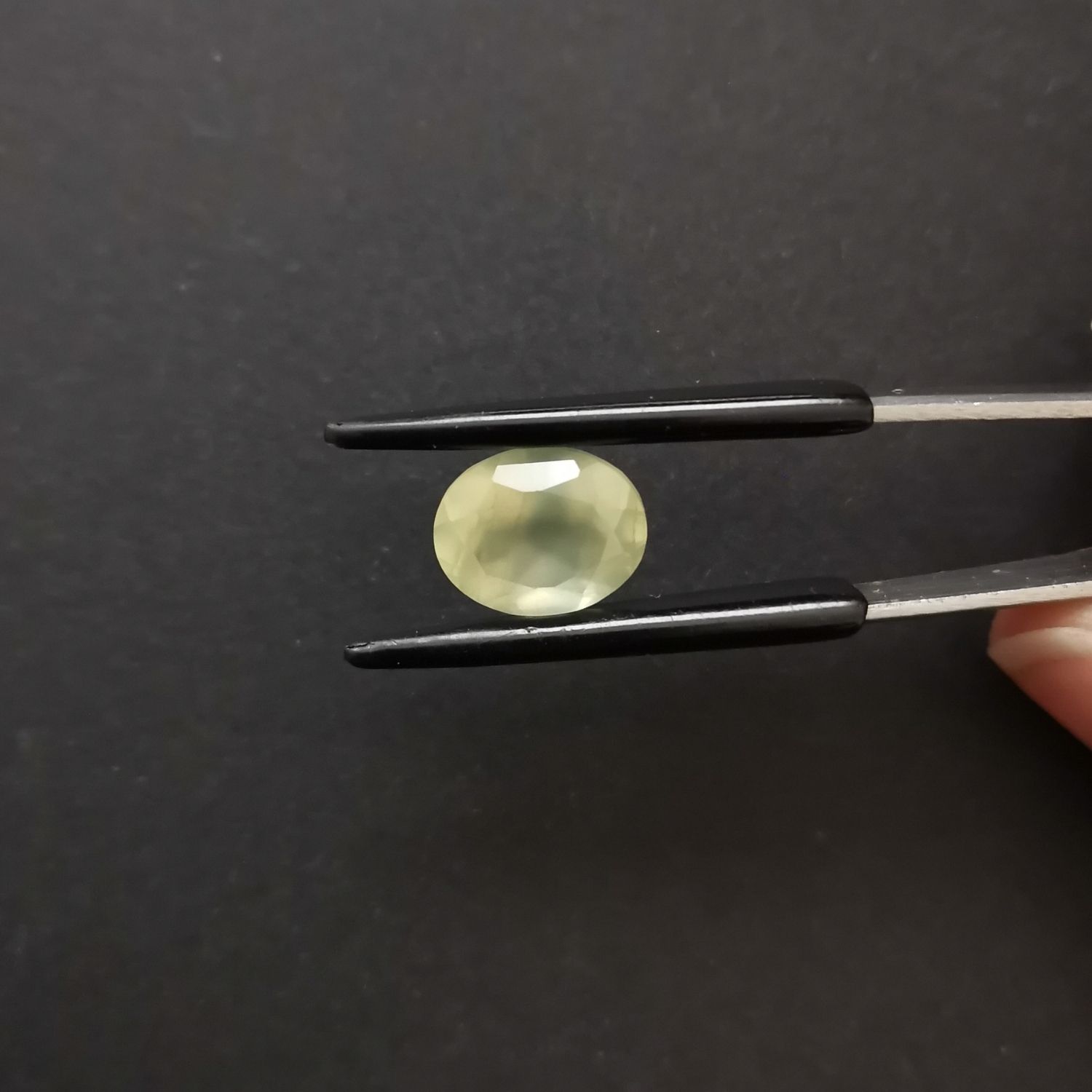 Crown view of the faceted prehnite oval against a black background.