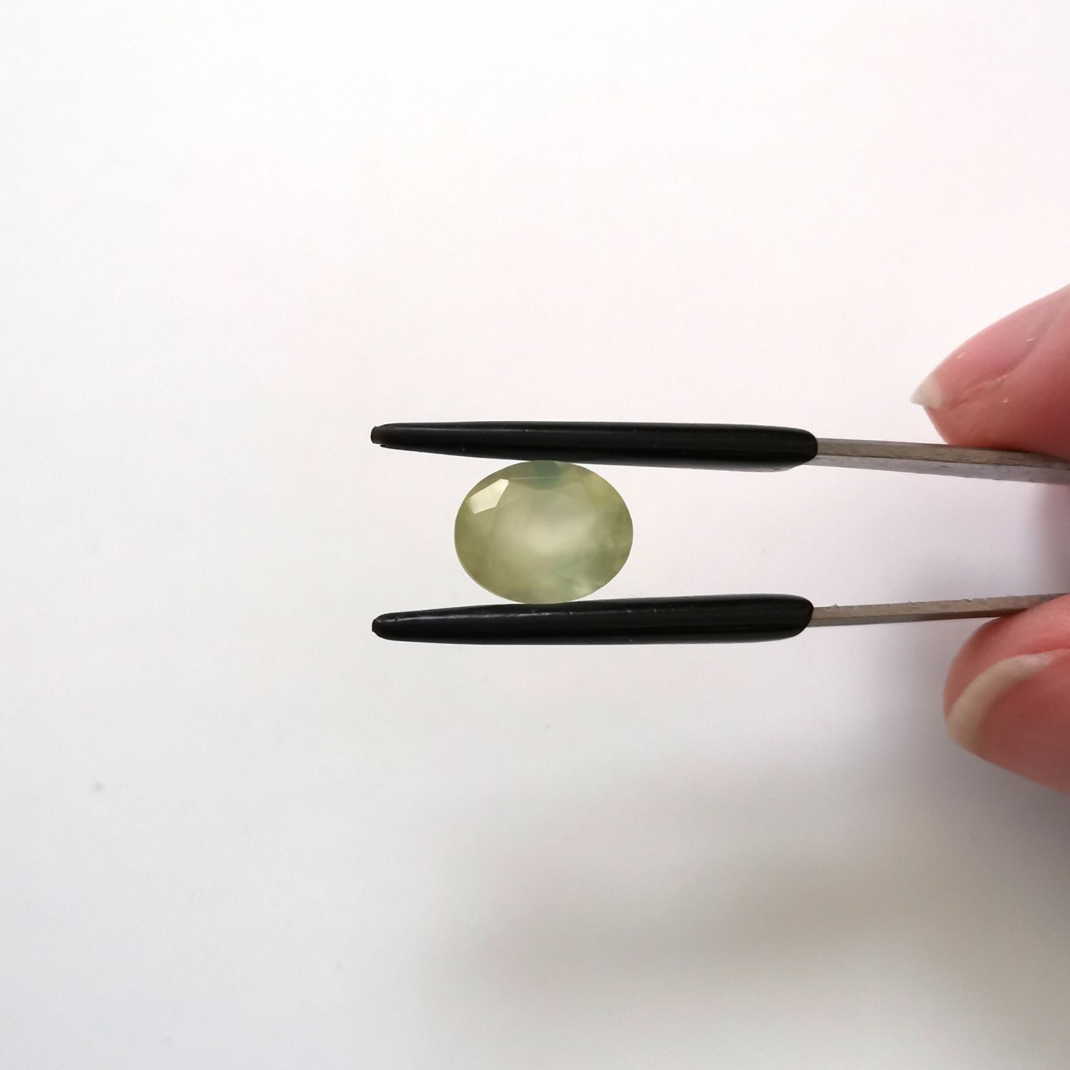 Crown view of the faceted prehnite oval against a white background.
