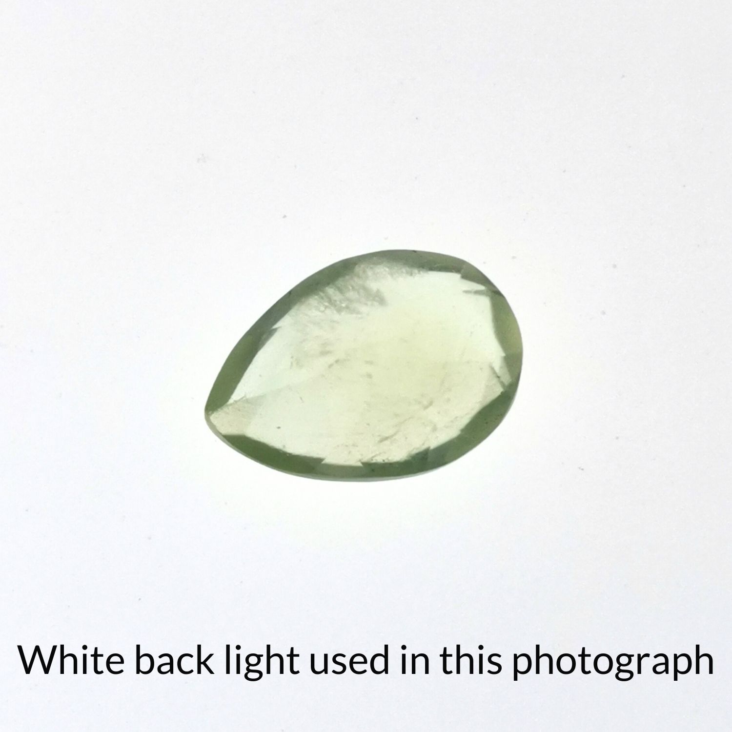 The faceted teardrop prehnite back-lit to highlight inclusions.