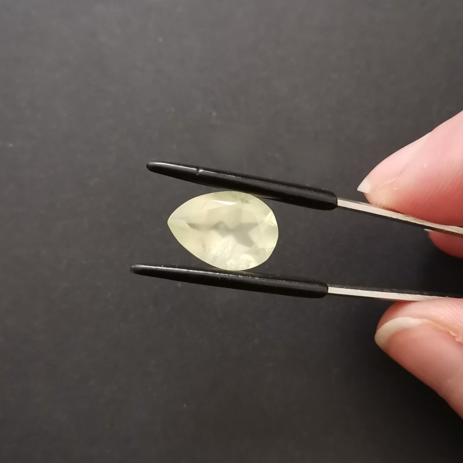 Crown view of the faceted prehnite teardrop against a black background.