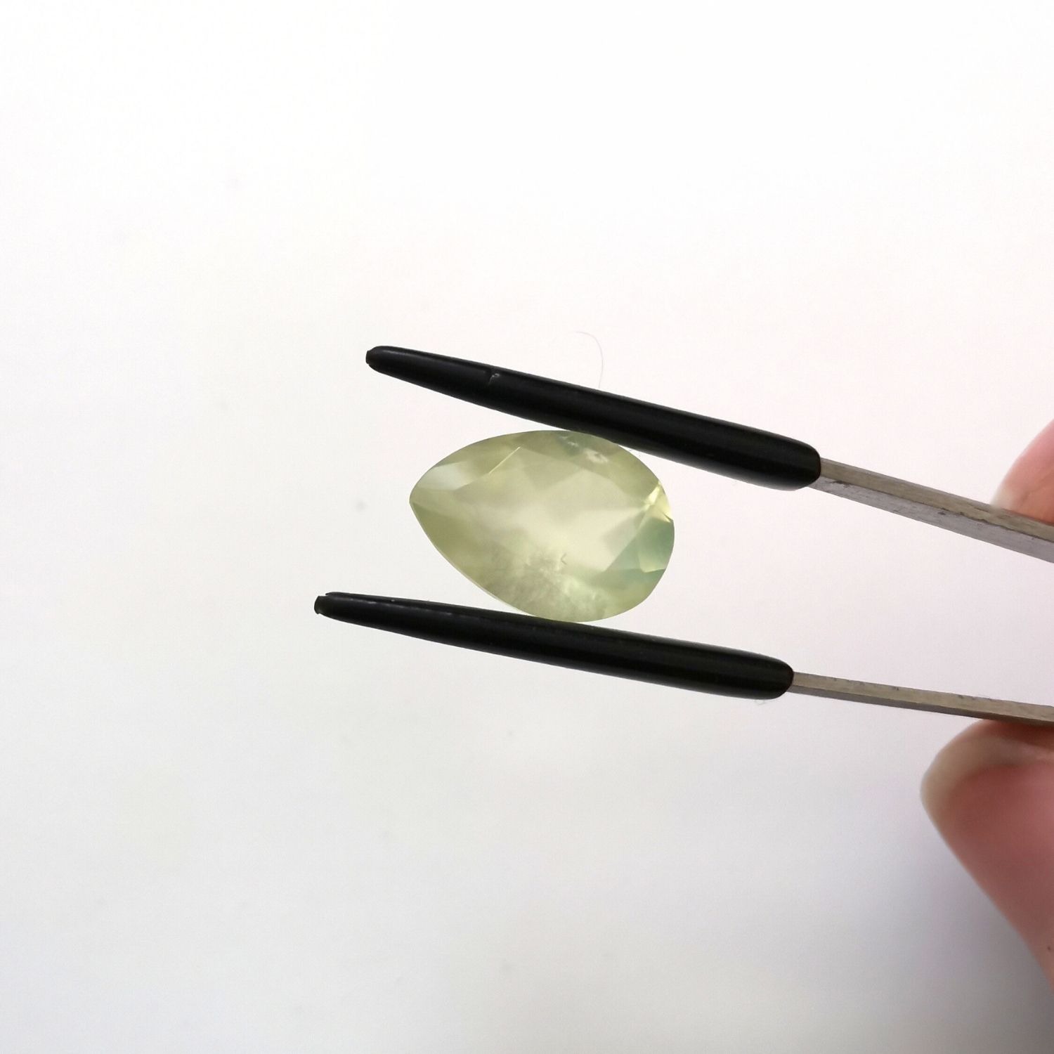 Crown view of the faceted prehnite teardrop against a white background.