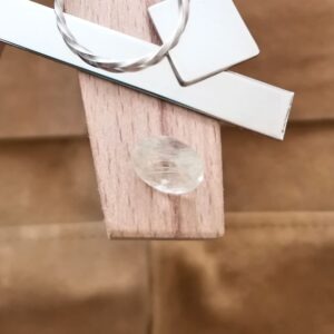 The golden rutilated quartz oval displayed on a jewellers bench peg with some sterling silver sheet and wire.