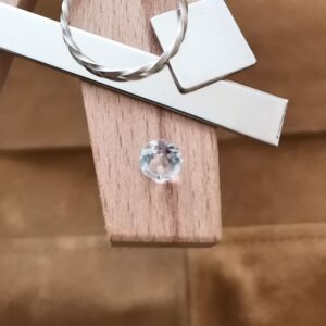 The clear goshenite round displayed on a jewellers bench peg with some sterling silver sheet and wire.