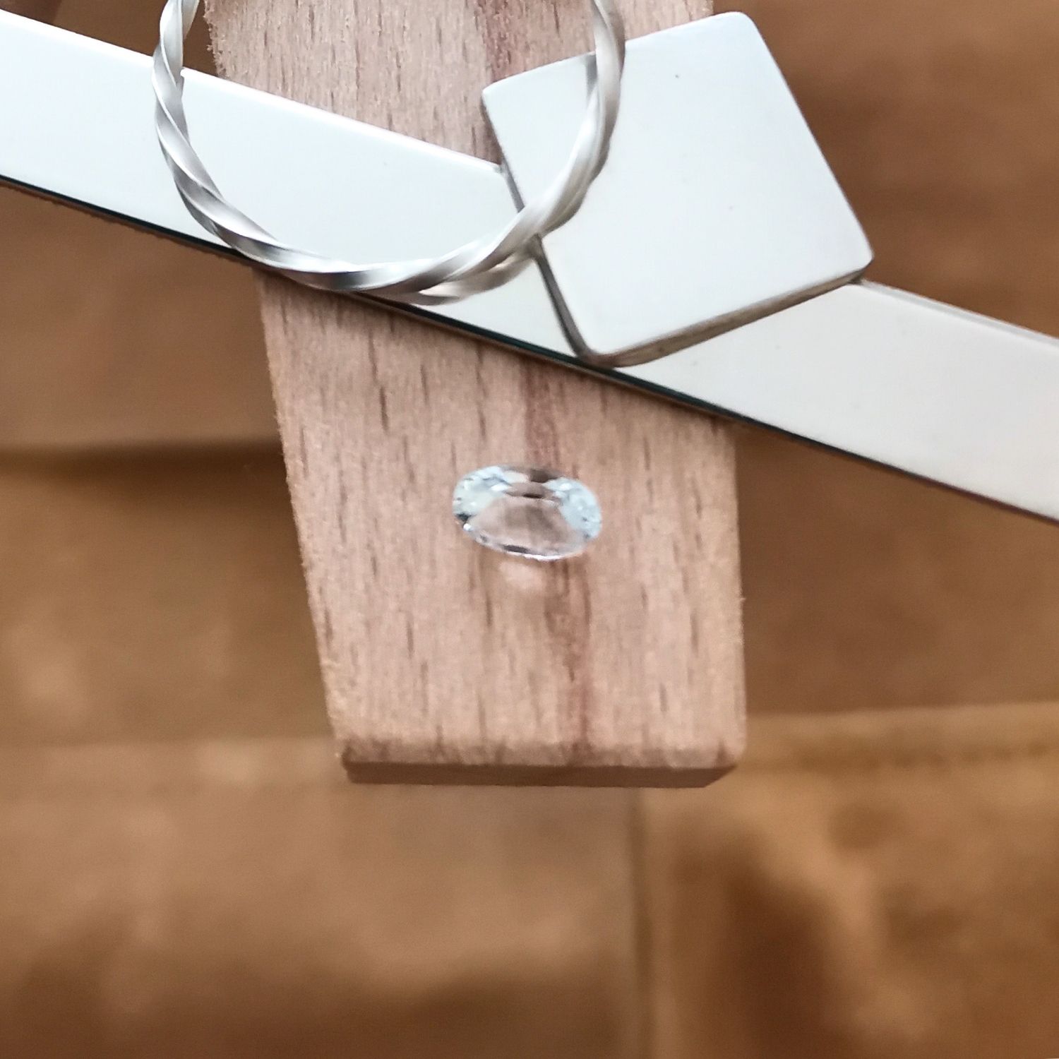 The white goshenite oval displayed on a jewellers bench peg with some sterling silver sheet and wire.
