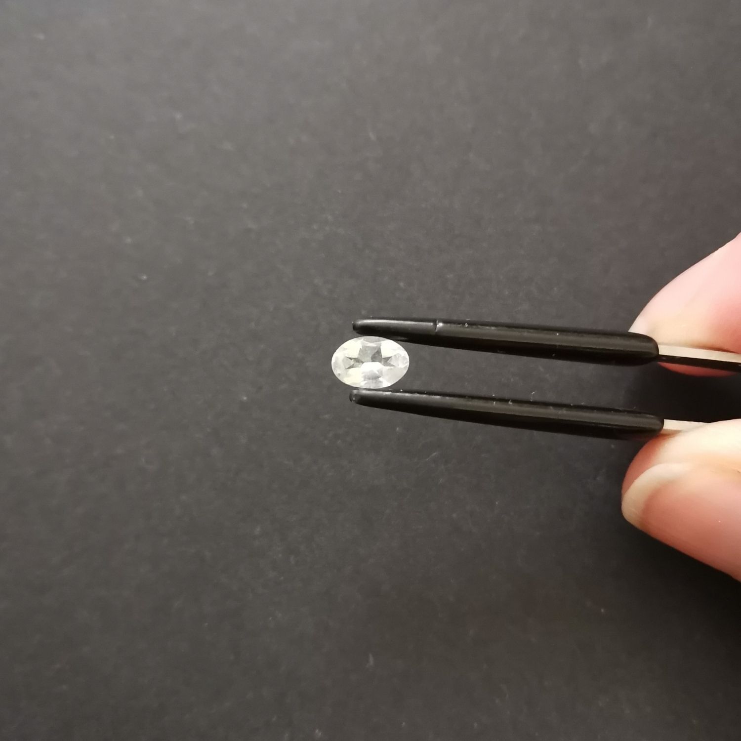 Crown view of the faceted goshenite oval against a black background.