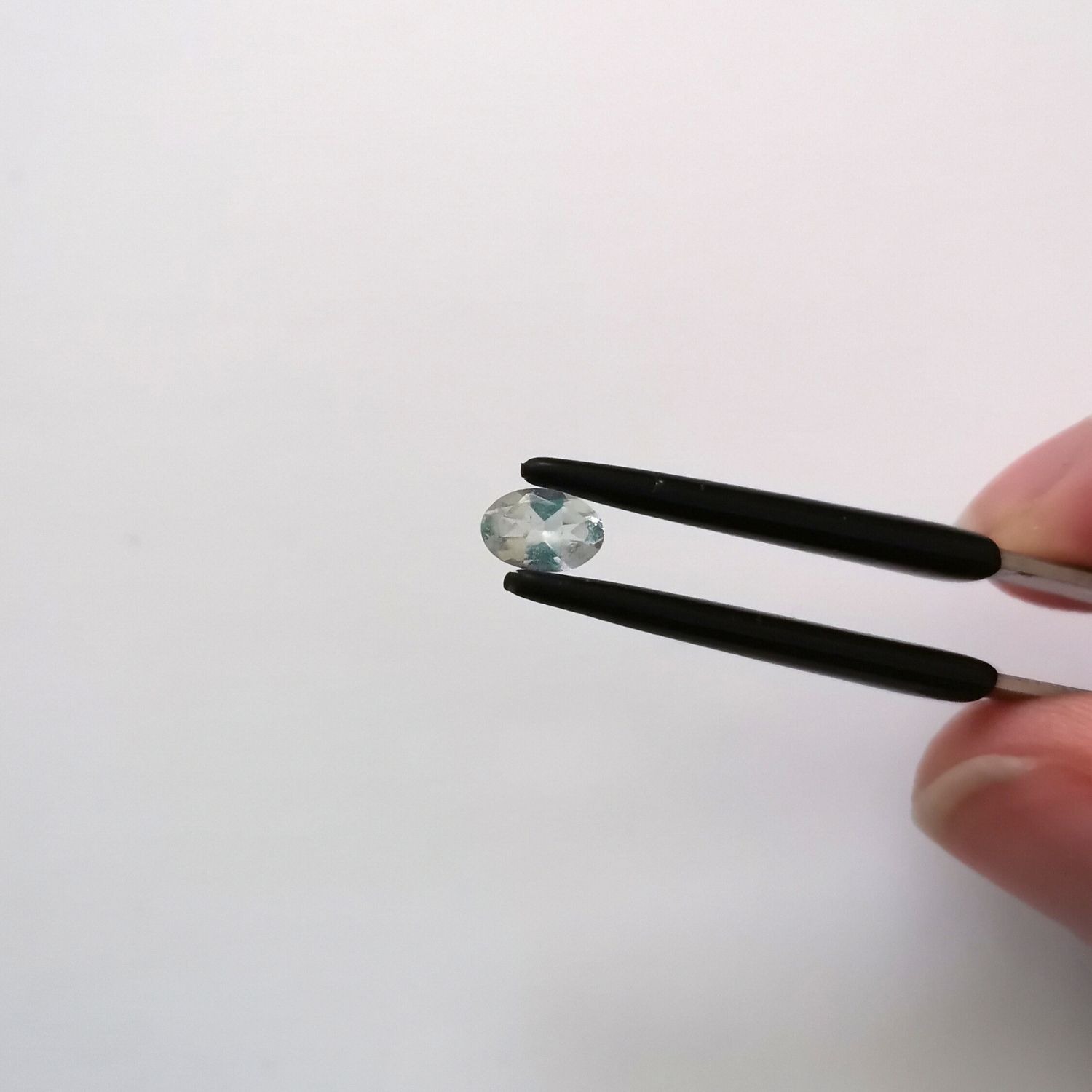 Crown view of the faceted goshenite oval against a white background.